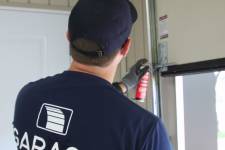 A man showing how to lubricate garage door rollers
